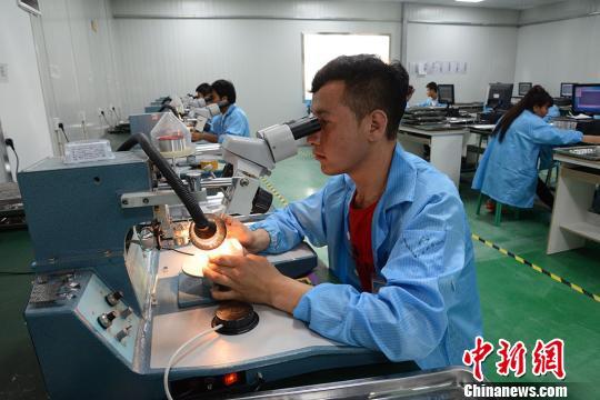 喀什广泓能源科技有限公司的生产车间,员工在对芯片产品进行质检.